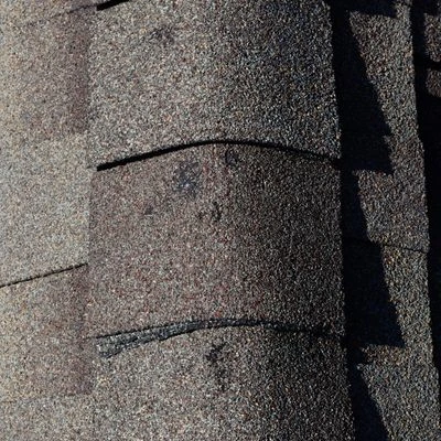 Close-up of lifted asphalt shingles indicating storm-related roof damage