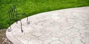 Stamped concrete patio featuring flagstone pattern in neutral tones with decorative metal garden chair