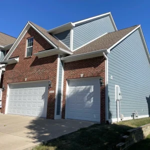 Home garage with brick and blue vinyl siding
