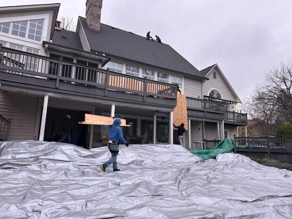 Moss Roofing roofers installing a home with a new roof, tarp covering the outdoor area for protection