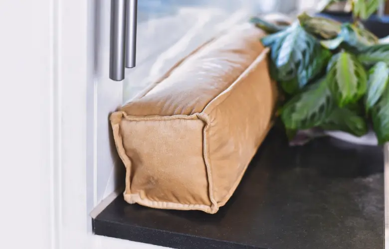 Draft stopper placed at base of door showing signs homeowners need window replacement in Central Indiana