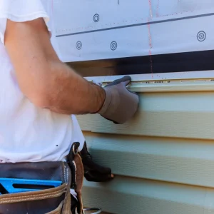 Contractor installing vinyl siding.