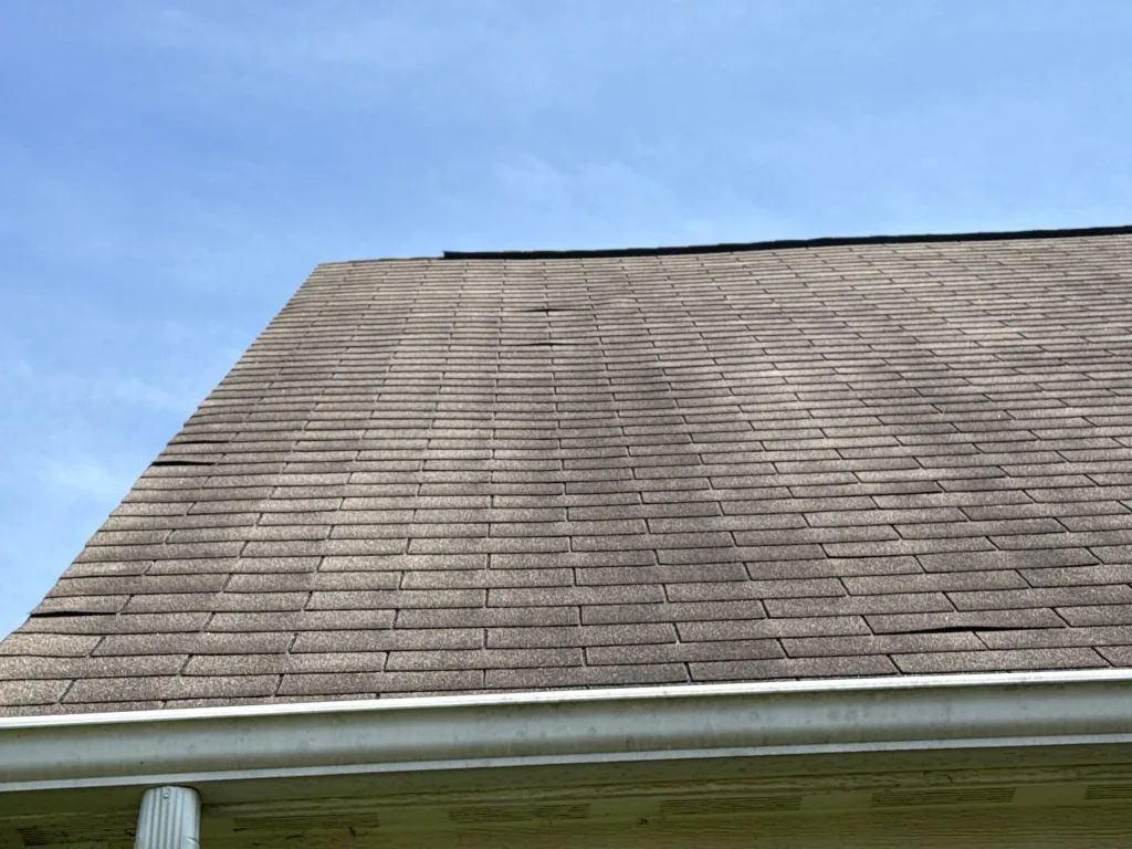 Before: damaged/aged roof shingles. Lifting shingles visible from ground