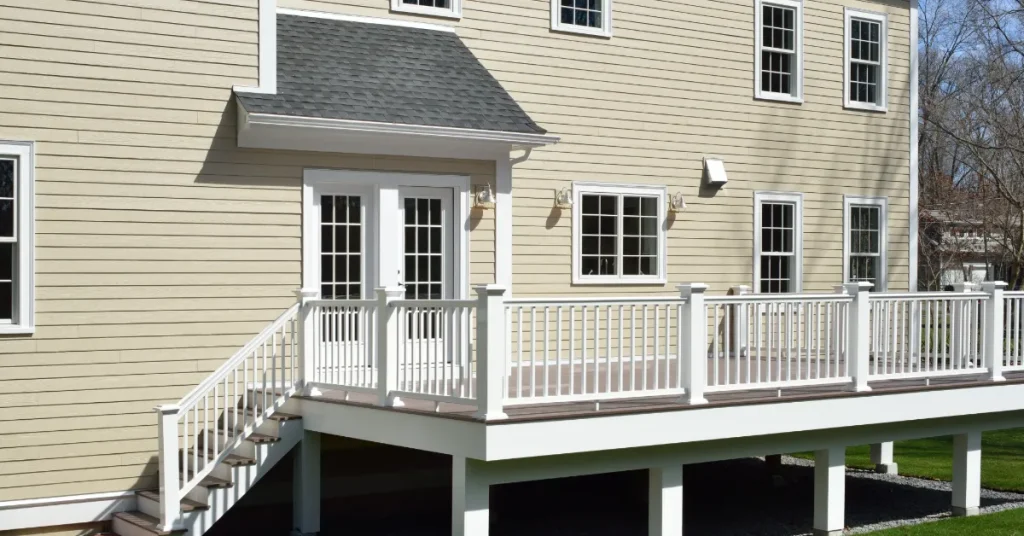 Tan colored vinyl siding on the exterior of a home that has an attached deck.